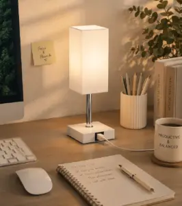 Minimalist white desk lamp on a modern home office desk with a notebook, pen, coffee mug, keyboard, and neutral decor in a warm, organized workspace.