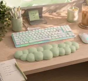 Mint green cloud keyboard wrist rest on a modern desk with white mechanical keyboard, mouse, candle, iced coffee, planner, and pastel office accessories.